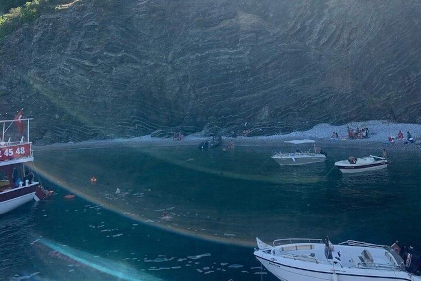 Un bote con el número 45 48 en su costado, un acantilado rocoso y varias embarcaciones más cerca de la orilla. 5