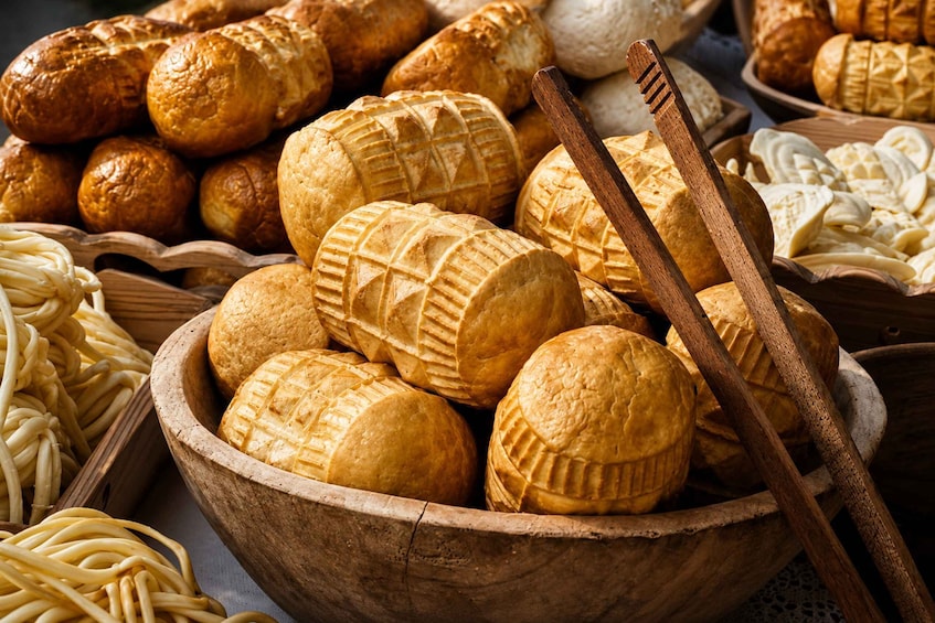 A variety of baked goods including bread rolls, baguettes, and pastries in a wooden bowl. 3