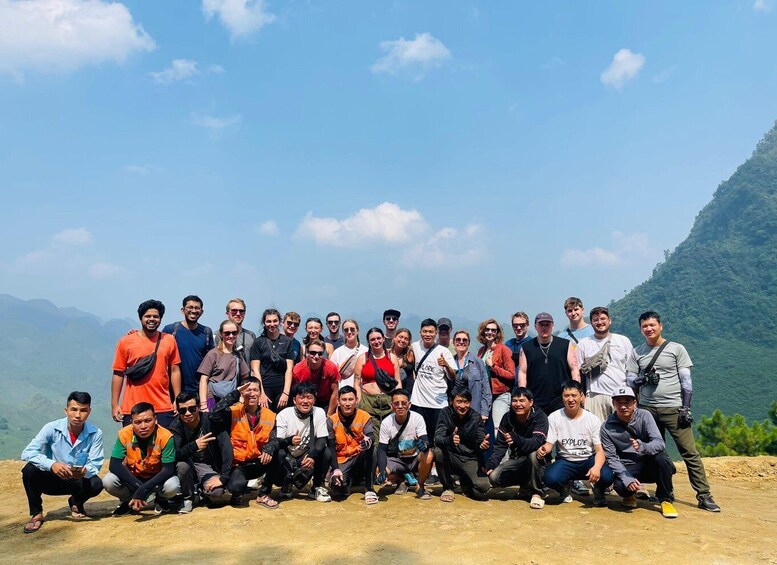 A group of people posing for a photo on a mountain with a clear sky. 2