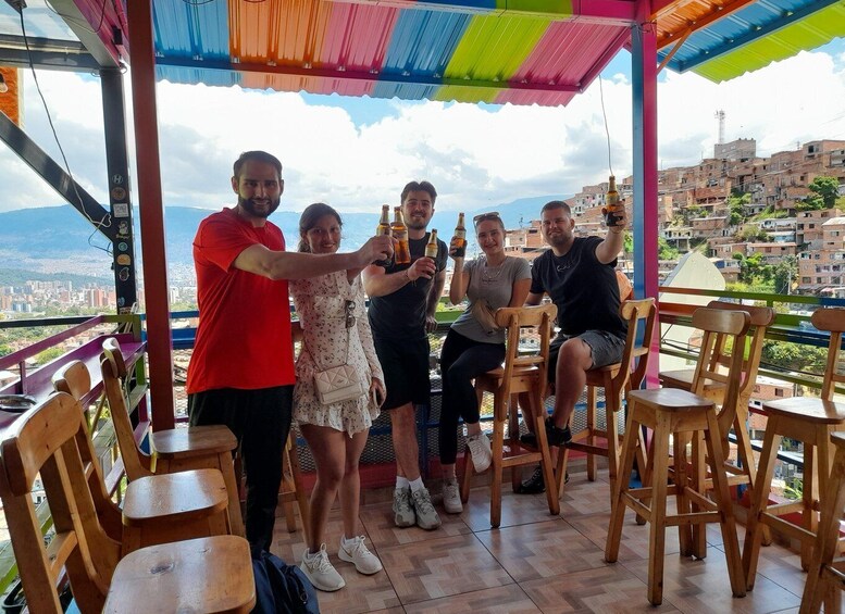 A group of people toasting with bottles on a terrace overlooking a cityscape. 1