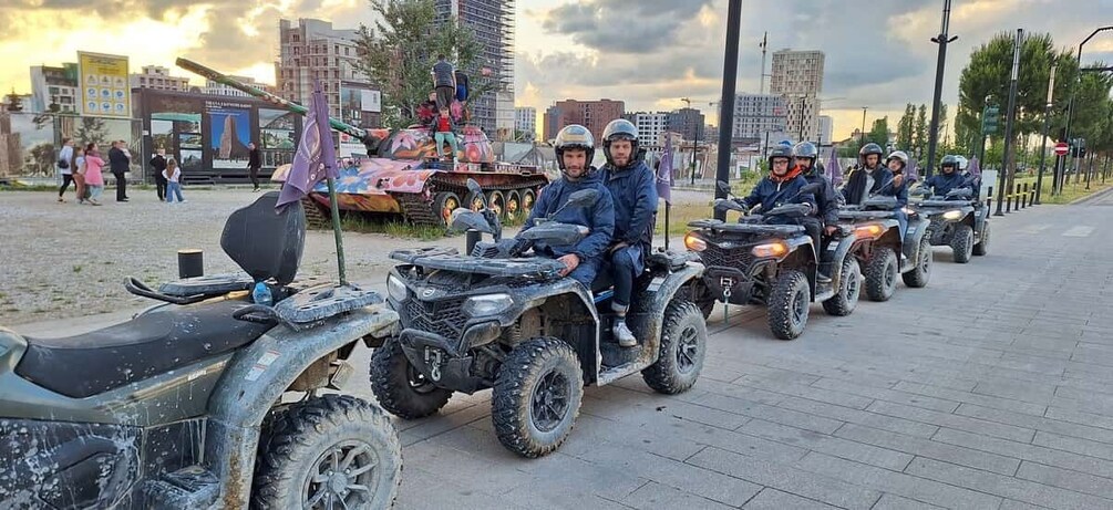 A group of people riding quad bikes on a paved path. 5