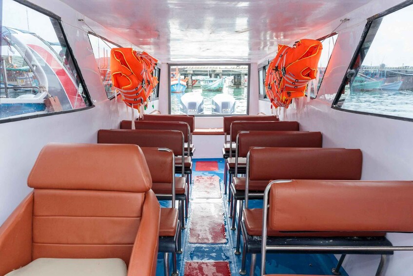 A boat interior with rows of brown leather seats and orange life jackets hanging from the ceiling. 2