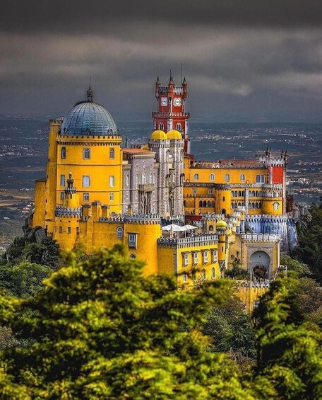 Pena Palace with its distinctive yellow and red architecture, a large dome, and a tower with a clock. 1