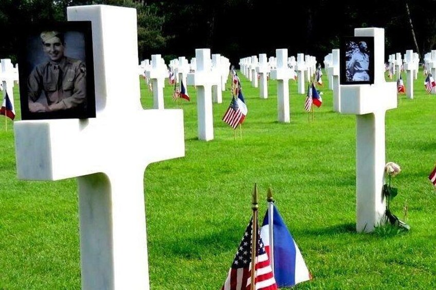 A cemetery with white crosses and American flags. 3