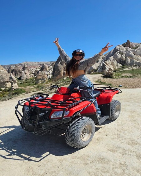 A person on a red ATV with a rocky landscape in the background. 5