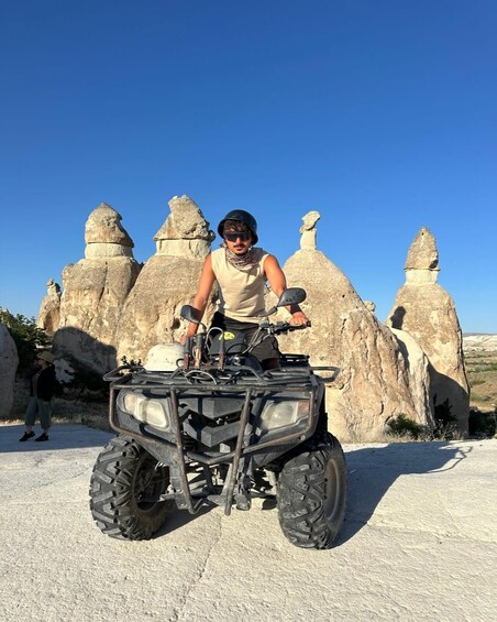 A person on an ATV in front of rock formations. 4