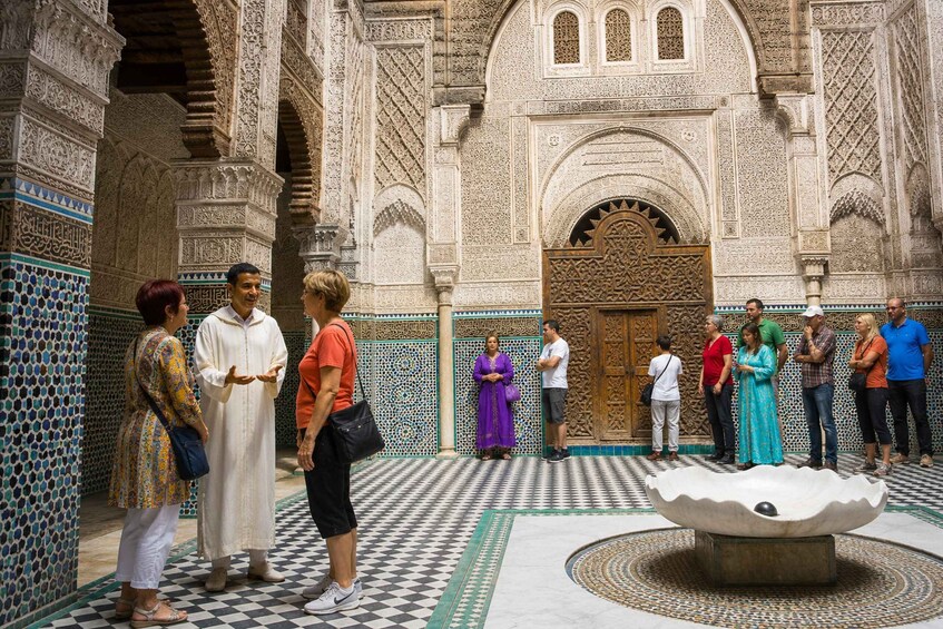 A group of people in a courtyard with intricate tile work and a large wooden door. 2