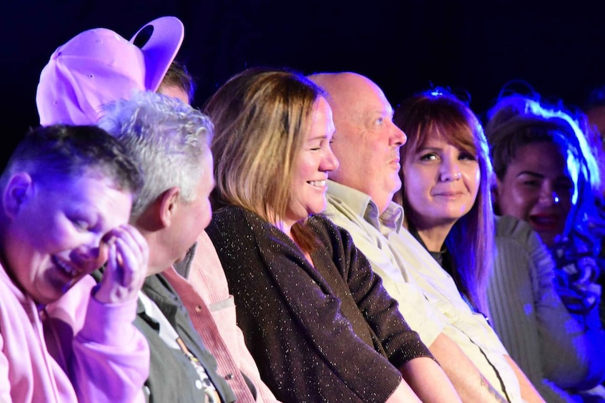 A group of people seated at an event with stage lighting. 5