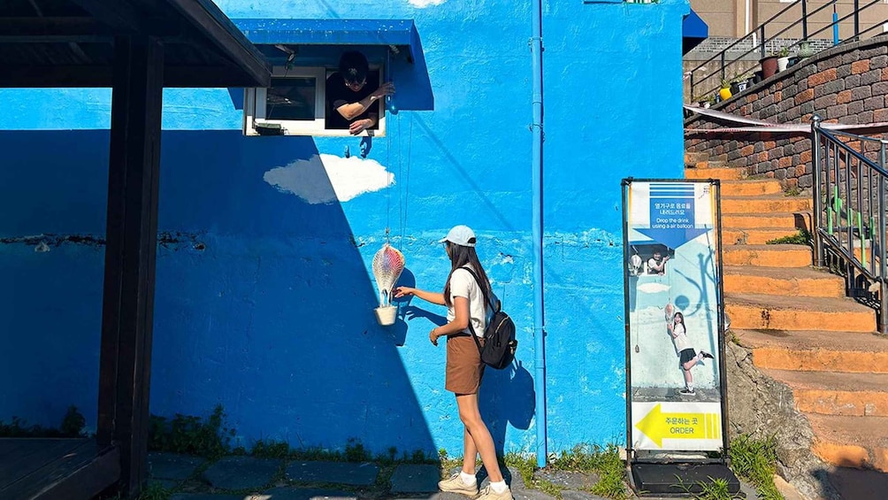 Une personne est en train de peindre un mur bleu, un escalier et une enseigne avec du texte en coréen. 3