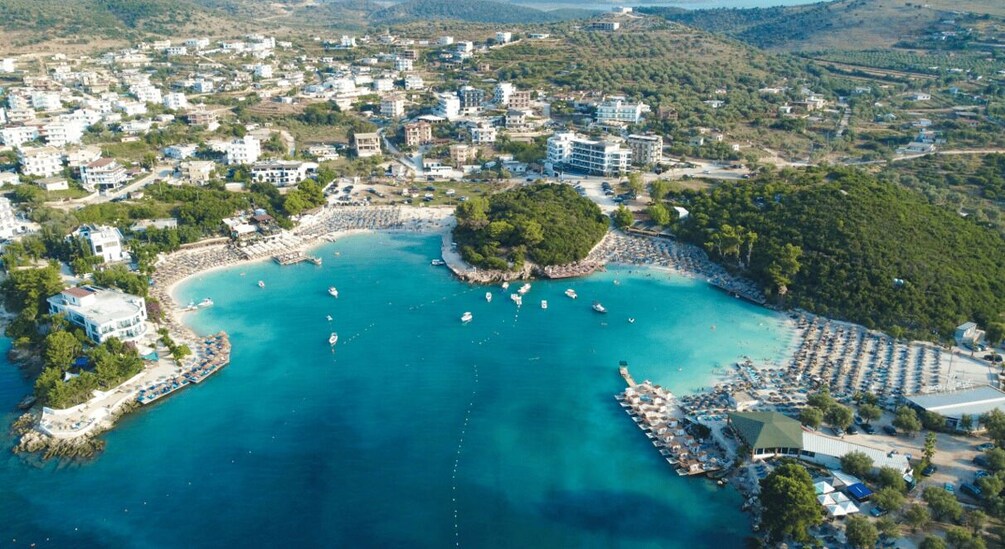 An aerial view of a coastal town with a marina, clear blue waters, and surrounding greenery. 5