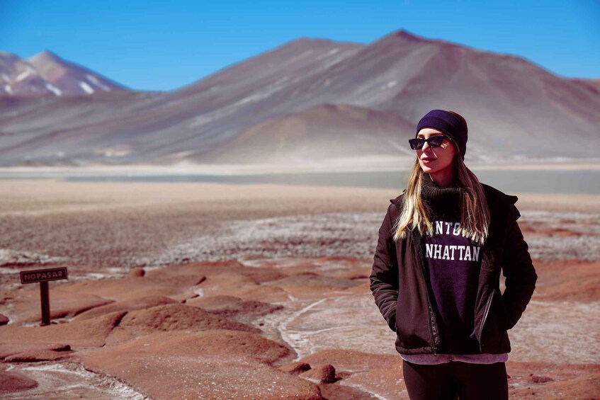 A person standing in a desert landscape with mountains in the background. 1