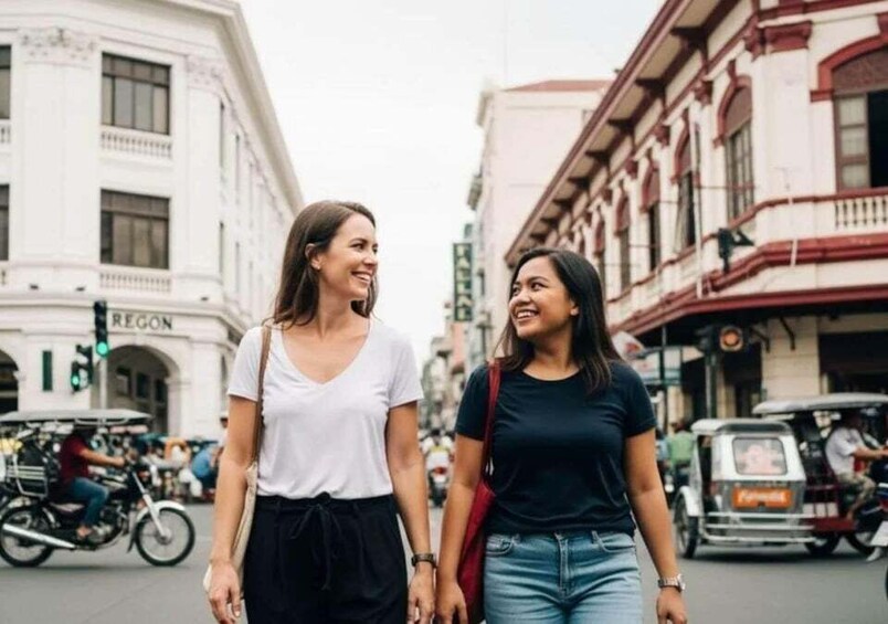 Two women walking on a city street with historic buildings and tuk-tuks in the background. 5