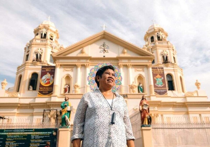 A person standing in front of a large, ornate church with two towers and a central dome. 3