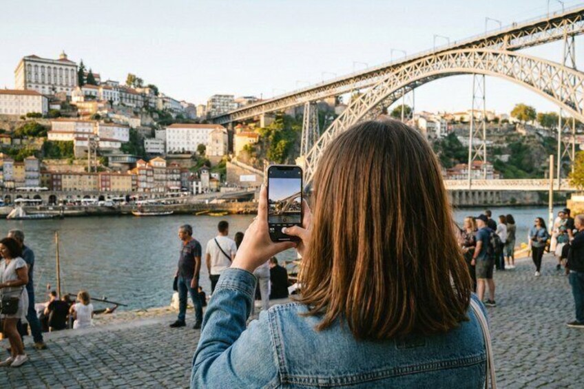 A person taking a photo of a bridge and buildings by the water. 2