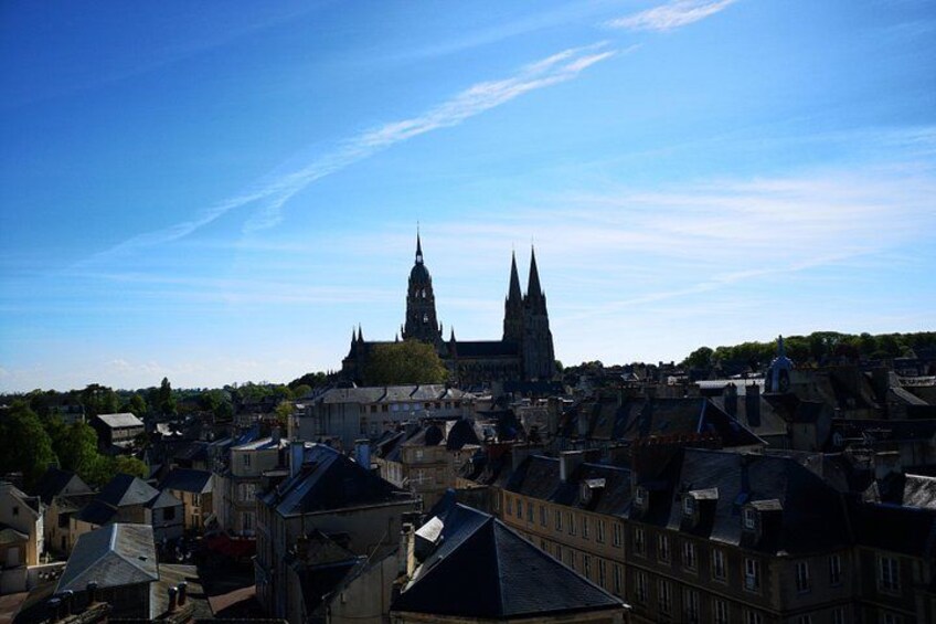 Een historische stad met een opvallende kerk met twee torens, omringd door traditionele gebouwen en een helderblauwe lucht. 1