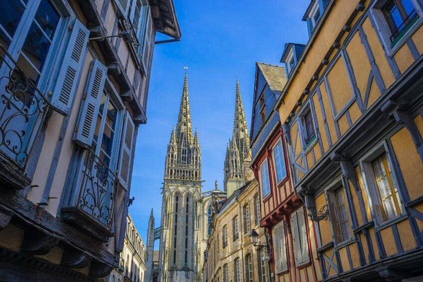 Une rue étroite bordée de bâtiments historiques, une cathédrale à deux flèches et un ciel d’un bleu limpide. 3