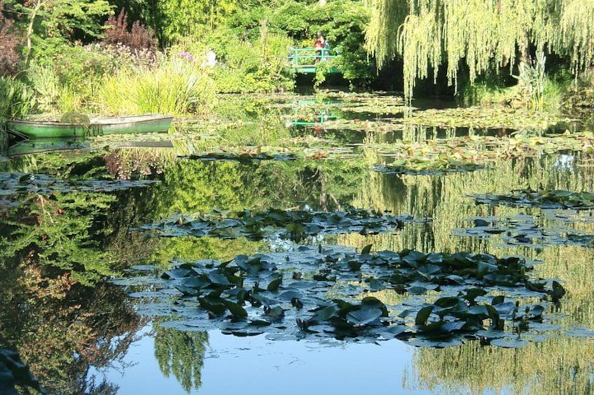Un étang parsemé de nénuphars, un saule pleureur et un bateau à rames. 4