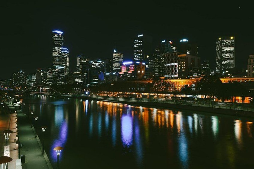 A nighttime cityscape with illuminated buildings reflecting on a river. 3