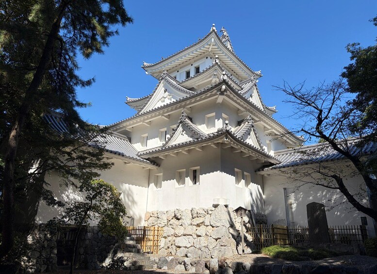 A traditional Japanese castle with multiple tiers, white walls, and a stone base. 2