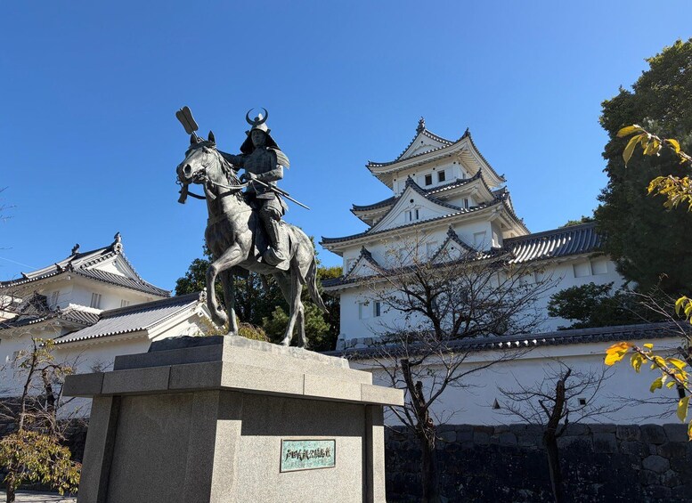 A statue of a mounted figure in front of a traditional Japanese castle. 1