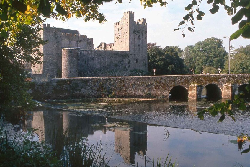 A historic stone bridge over a calm river, reflecting a castle in the background. 2