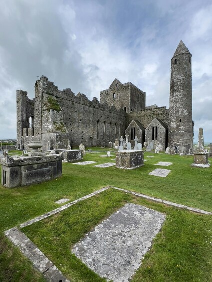 An ancient stone castle with ruins and a cemetery in the foreground. 5