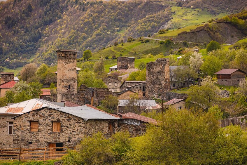 A historic village with stone buildings and a prominent tower. 1