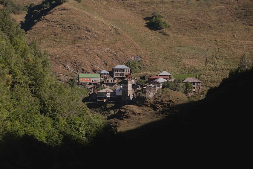 A hillside settlement with several buildings, including a prominent stone structure and a house with a green roof. 5