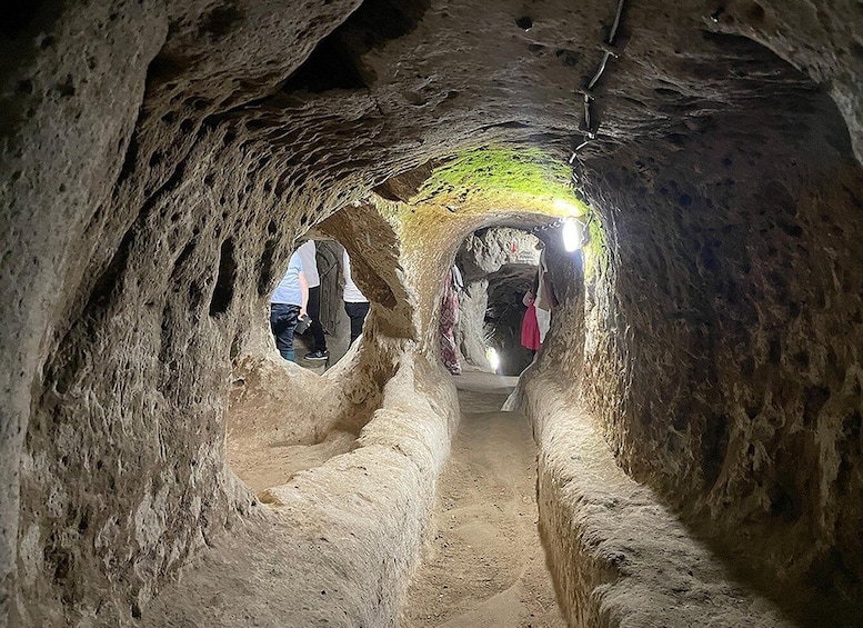 A narrow cave passage with rough walls and a light source at the end. 5