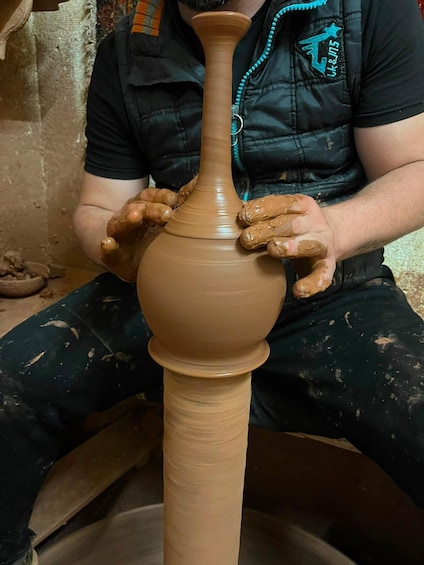 A person shaping a clay pot on a pottery wheel. 2