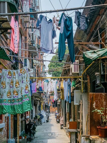 A narrow alley with clothes hanging on lines, brick buildings, and parked motorcycles. 4