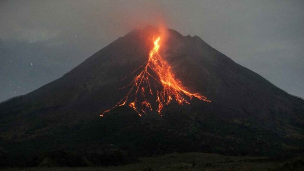A volcano erupting with lava flowing down its sides. 2