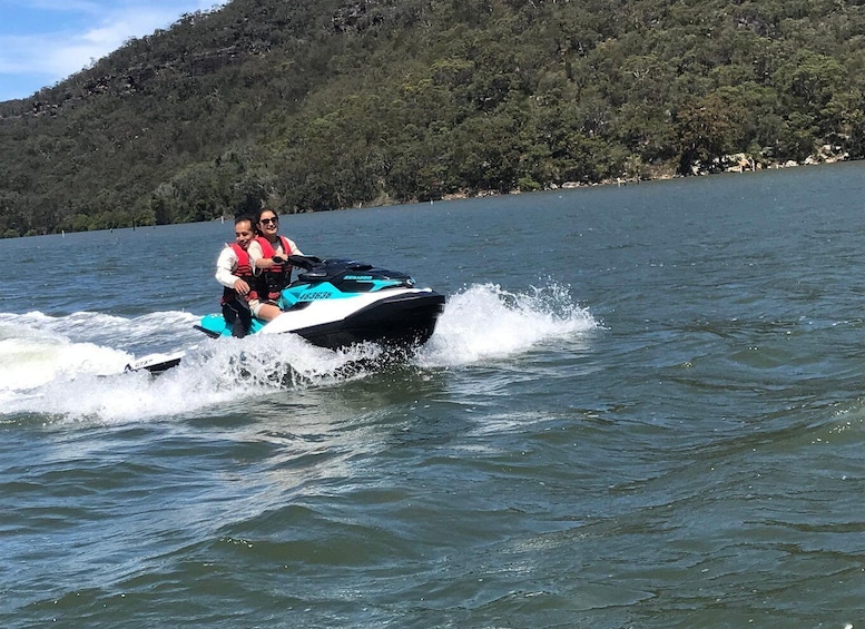 A person riding a jet ski on a lake with a forested hill in the background. 2