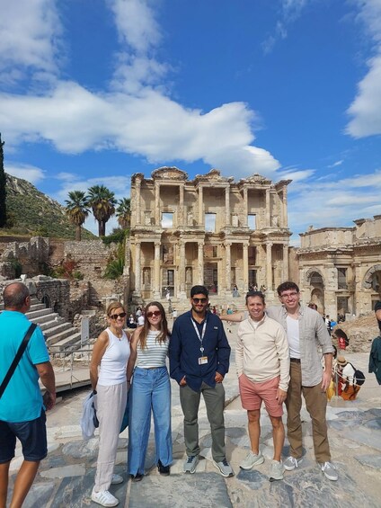 A group of people standing in front of an ancient ruin with columns and steps. 4