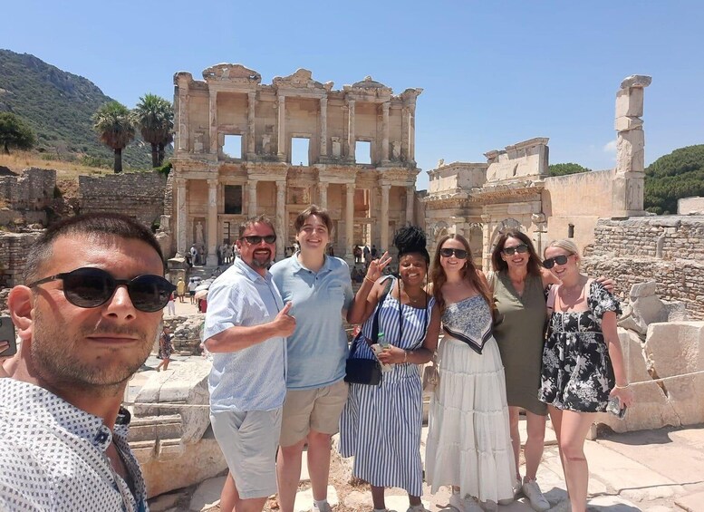 A group of people standing in front of ancient ruins with columns and a large stone structure. 5