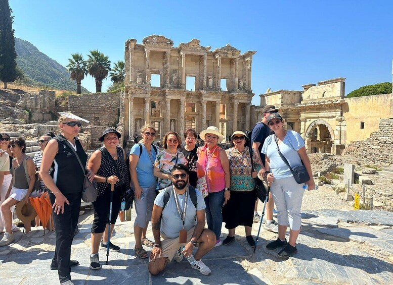 A group of tourists at the ruins of an ancient structure with columns and arches. 1