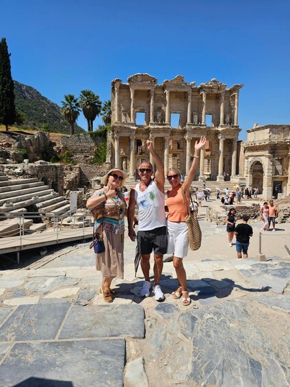 A group of people standing in front of ancient ruins with columns and steps. 1