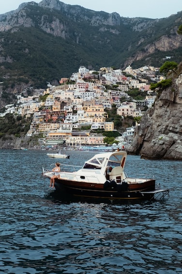 A boat on calm water with a town on a hillside in the background. 4