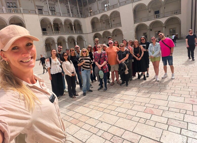 A group of people standing in a courtyard with a building featuring arches in the background. 3