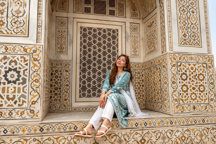 A person sitting on a bench with intricate tile patterns and a decorative window. 3