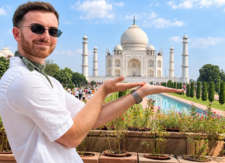 A person in front of the Taj Mahal with a pool and potted plants in the foreground. 1
