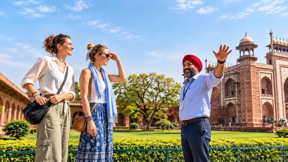 Three people standing in a garden with a large historical building in the background. 2