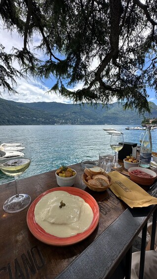 A lakeside table with food, drinks, and boats in the background. 2