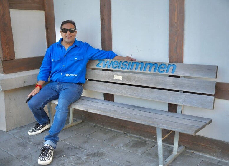 A man sitting on a wooden bench with the words "Zwiesimmer" on it. 4