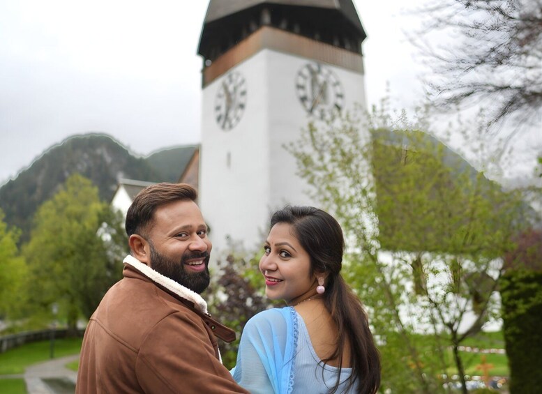 A couple standing in front of a clock tower with a mountainous background. 2