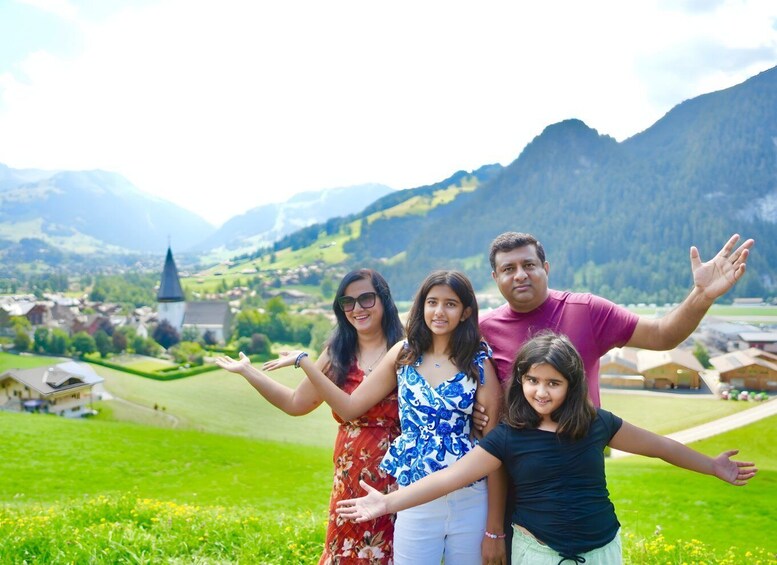 A family standing in a grassy field with a mountain and a church in the background. 1