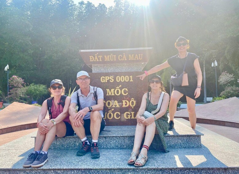 Four people sitting on steps with a sign in the background. 5