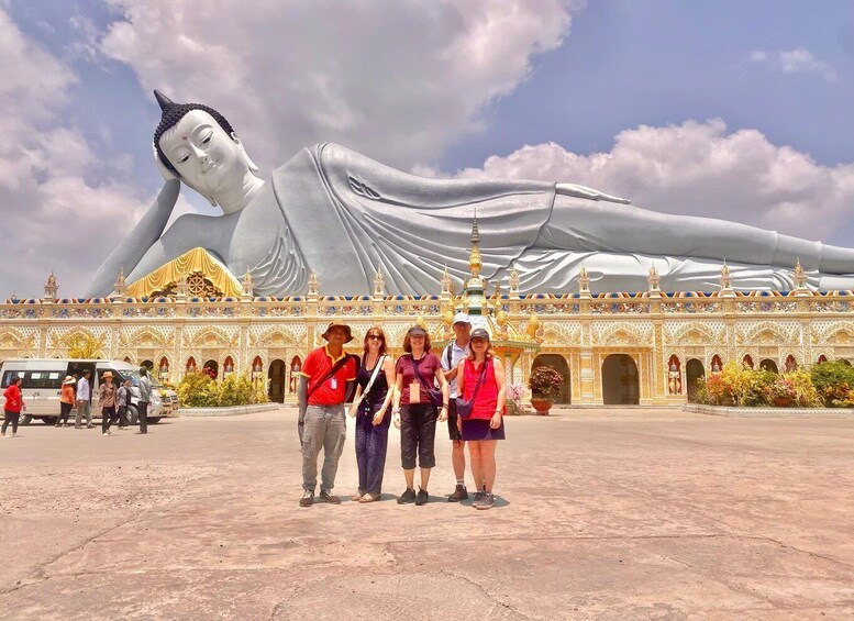 A large reclining Buddha statue in front of a temple with ornate architecture. 1