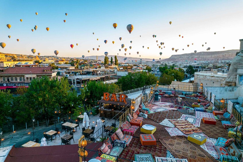 A rooftop bar with colorful seating and hot air balloons in the background. 3