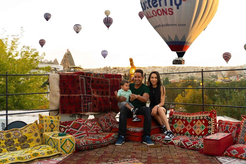 A family on a rooftop with a view of a cityscape and hot air balloons in the sky. 5